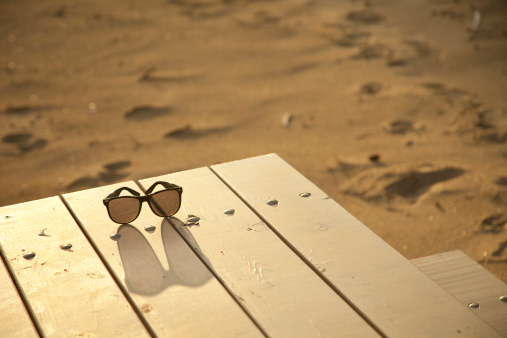 Sunglasses on a picnic table at the beach.
