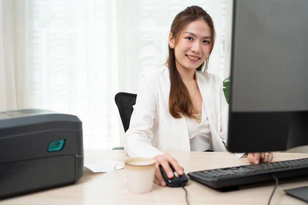 istock Asian woman using personal computer to printing data to printer on label sticker barcode with QR code. 1827592924