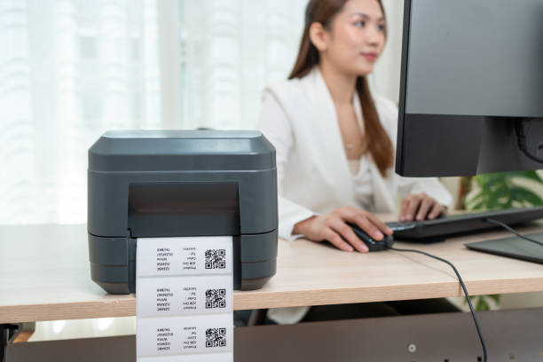 istock Asian woman working using personal computer to printing the QR code on the white sticker in office. 1827593953
