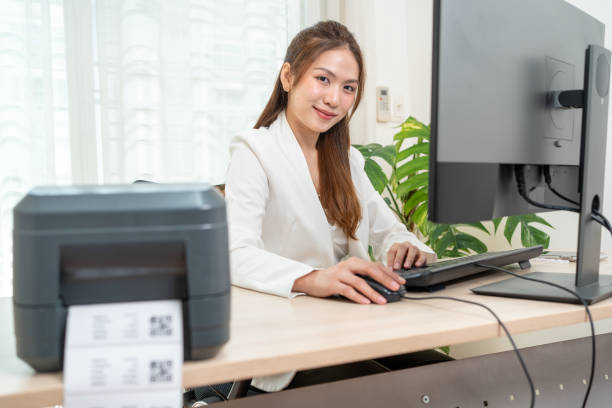 istock Asian woman working using personal computer to printing the QR code on the white sticker in office. 1827593960