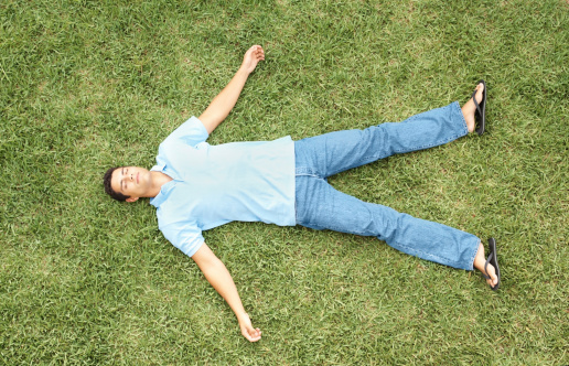 Top view of a casual young man resting on grass at a lawn