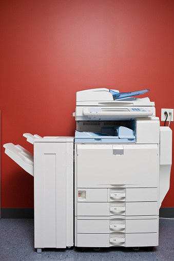 Office Photocopier inside a supply room in front of a red wall