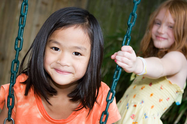 istock Cute girls playing at swingset 182760369