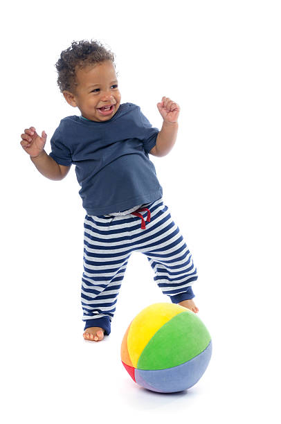 A baby smiling while playing football against a white background