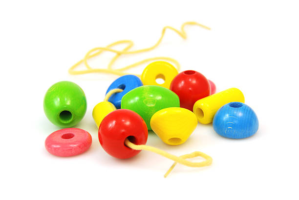 big wooden lacing beads helps children with hand-eye coordination - shallow DOF - isolated on white