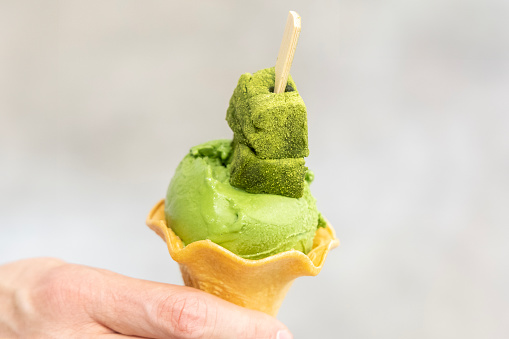 An ice cream cone with bright green matche ice cream scoop on top.