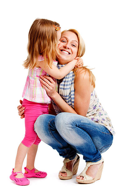 Smiling mother embracing young daughter on white background stock photo