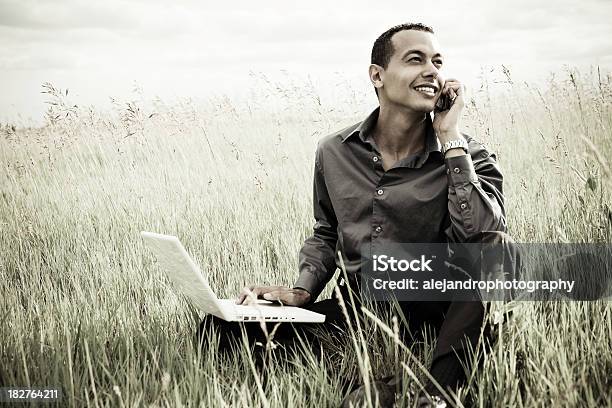 Latinomann Auf Laptop Und Handy Stockfoto und mehr Bilder von Am Telefon - Am Telefon, Arbeiten, Berufliche Beschäftigung