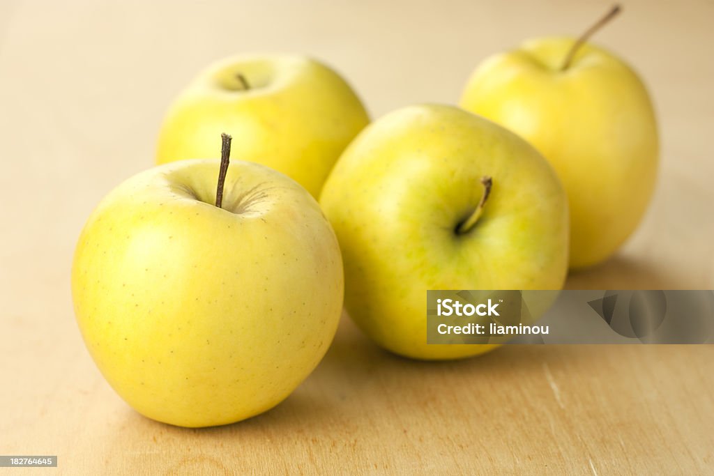 yellow apples four yellow apples on wooden table Apple - Fruit Stock Photo