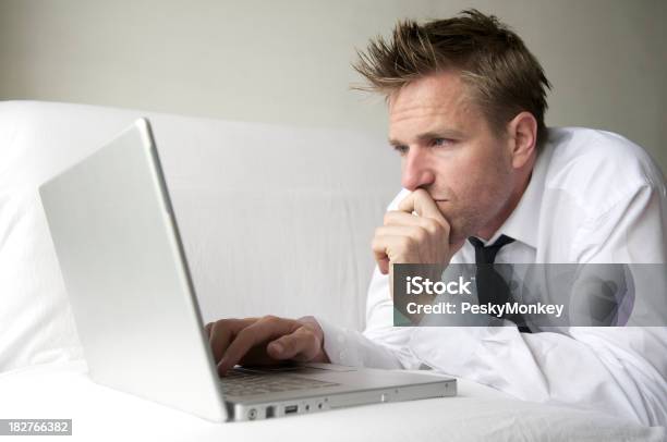 Hombre En Camisa Blanca Y Negro De Cordones Browses En Ordenador Portátil Foto de stock y más banco de imágenes de 25-29 años