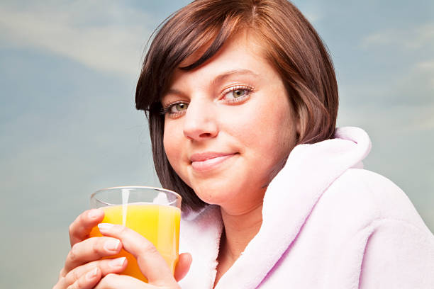 istock young woman drinking orange juice 182766387