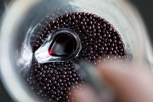 Homemade Elderberry (Sambucus) Extract A ladle straining off Elderberry Extract within large glass jar. The extract is created by steeping the berries of Sambucus Nigra in alcohol for at least three months. It is proven to have medicinal properties and cited as a very good remedy for flu. elderberry photos stock pictures, royalty-free photos & images