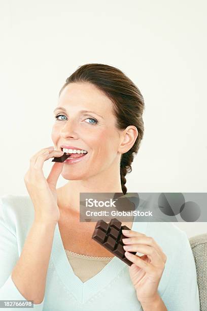 Feliz Mujer Madura Disfrutando De Un Bar De Chocolate Negro Foto de stock y más banco de imágenes de Chocolate