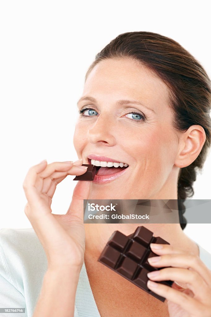 Jolie femme manger une chocolat contre blanc - Photo de 40-44 ans libre de droits