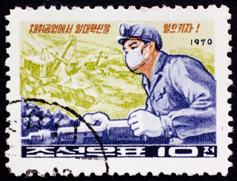 North Korea postage stamp from 1971 with a drawing of youth holding books and red flags on the background