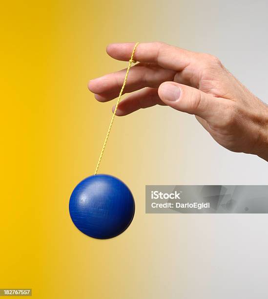 Masculino Mão Jogando Com Um Blu Yoyo Sobre Fundo Amarelo - Fotografias de stock e mais imagens de Ioió