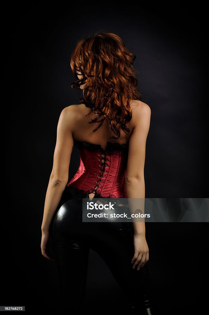 back of a nice woman dressed with red corset woman isolated on black, being dressed in latex panties and red corset. Sensuality Stock Photo