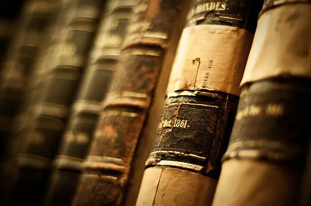 Old books from 1861 stacked in library. Shoot at 400 iso due to low lighting conditions, Visible grain.