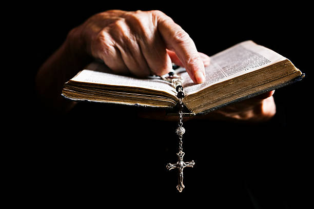 Faith "Old, wrinkled hands point out a text in an equally old Holy Bible. A rosary marks the place. Shot with Canon EOS 1Ds Mark III." nun praying cross human hand stock pictures, royalty-free photos & images