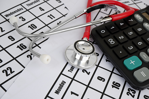 Cost of medical examination concept, stethoscope and calculator on calendar background