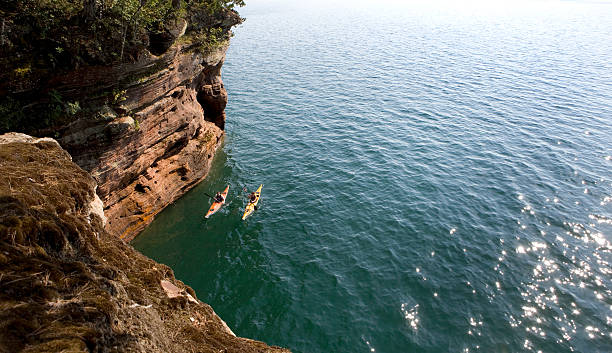 Sea Kayaking Couple sea kayaking along the cliffs of Lake Superior. bayfield county stock pictures, royalty-free photos & images