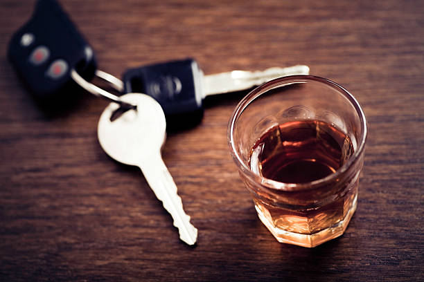 A glass of whisky and a set of car keys on a wooden table stock photo