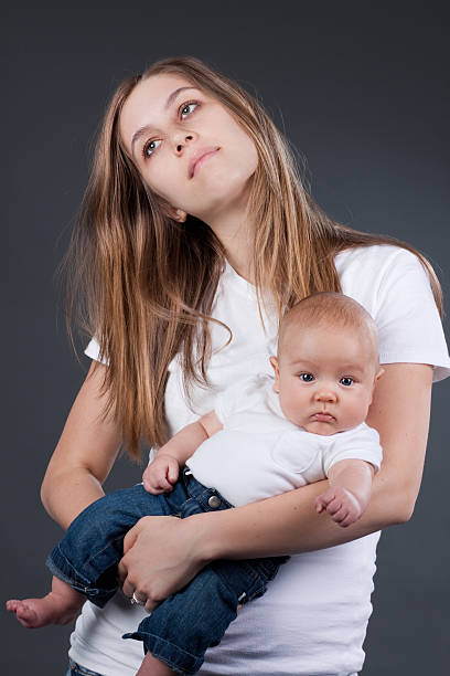 уставший молодая мать с baby - teenage pregnancy mother social issues family стоковые фото и изображения