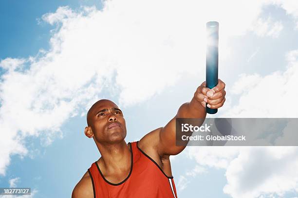 Upward View Of An Athlete Holding A Baton Against Sky Stock Photo - Download Image Now