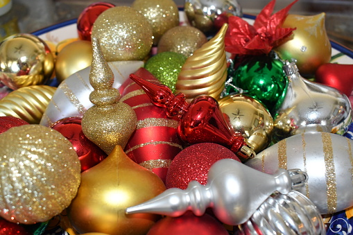 Uniquely shaped sizes, colors of Christmas tree ornaments fill a decorative bowl