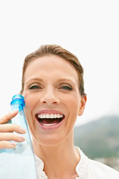Portrait of an excited mature lady holding a water bottle