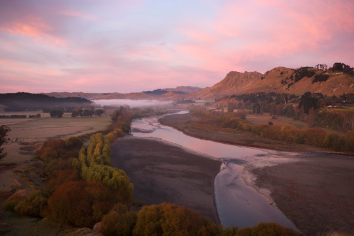 Te Mata Peak with the Tukituki River in the foreground and pink and purple cloud at sunrise.