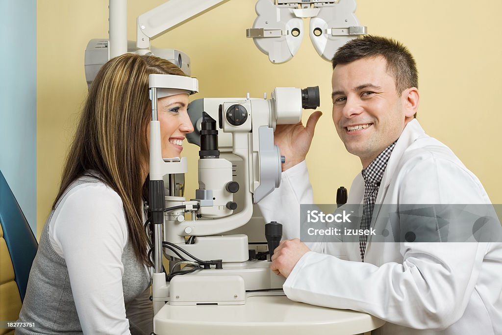 Optometrist Eye Exam Tonometer Optometrist looks at camera while examining the eyes of a young woman patient with a tonometer. 30-34 Years Stock Photo