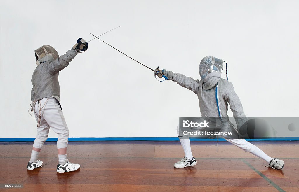 Young Fencers Bouting Full length shot of two young boys fencing with sabres.   Fencing - Sport Stock Photo