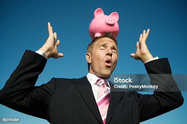 Businessman Tries To Balance Piggy Bank On Head Stock Photo - Download Image Now - Financial Advisor, Humor, Adult