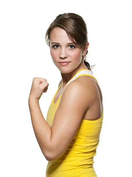 Studio portrait of attractive young woman flexing her arm in fitness clothing against white background.