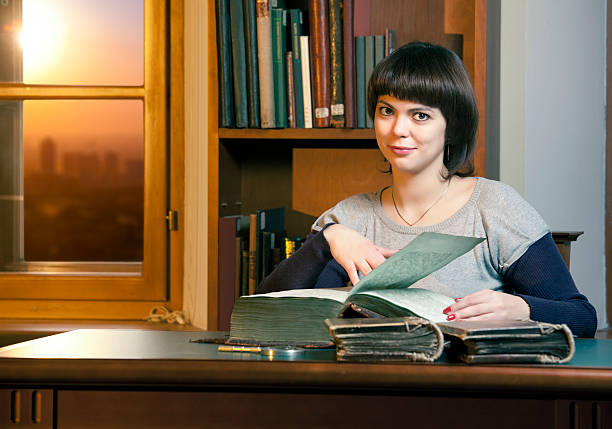 istock Young woman reading ancient books in library 182775366
