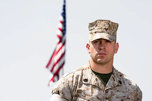 Marine standing in front of flag.