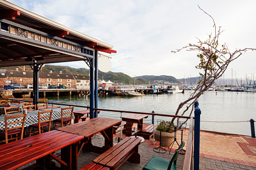 Restaurant at the waterfront in Simonstown, Western Cape, South Africa, in the distance shark diving and whale watching boat trips