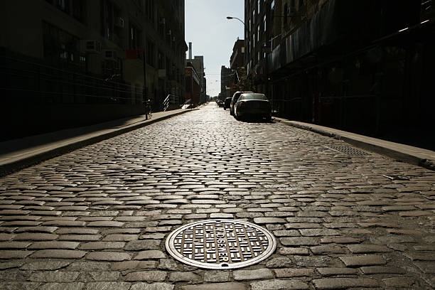 Deserted Brooklyn DUMBO Cobblestone Backstreet Sunrise Drain Cover NYC Sewer stock photo