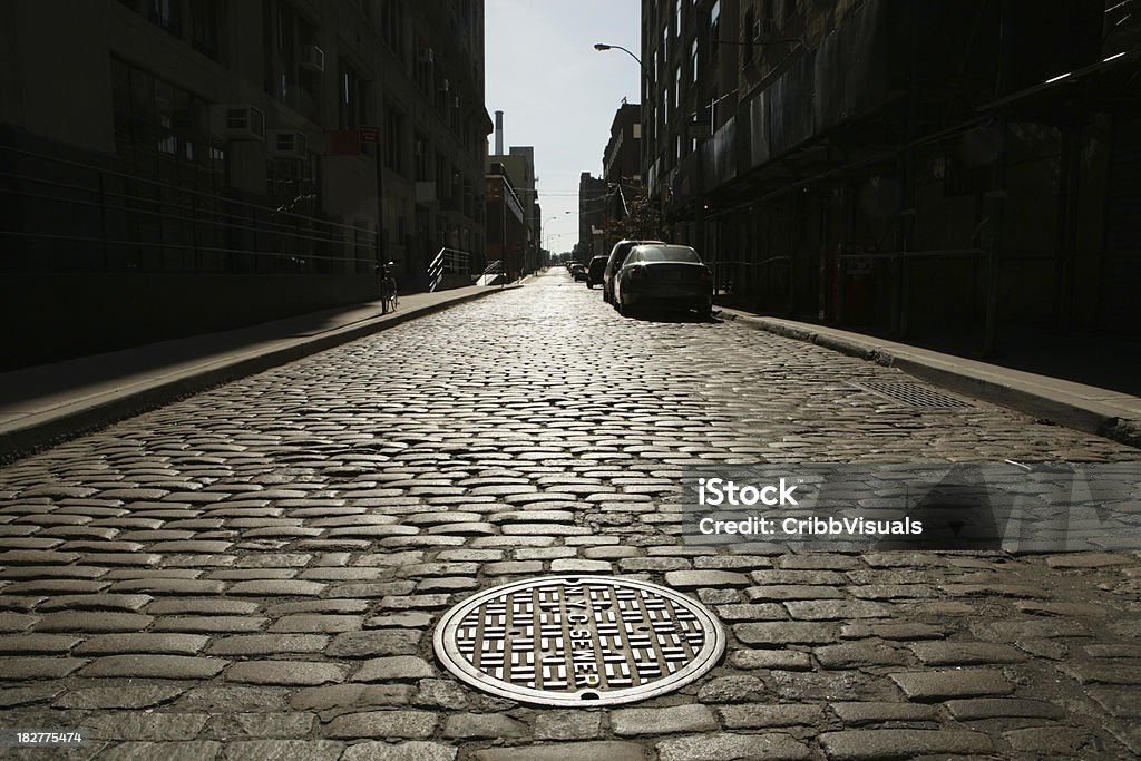 Необитаемый Brooklyn DUMBO Булыжник Backstreet Sunrise Drain Cover NYC Канализационная труба - Стоковые фото Нью-Йорк роялти-фри
