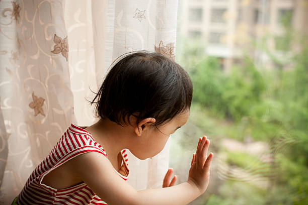 istock Little girl looking out window 182776109