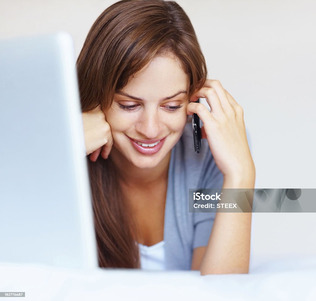 Lächelnde junge weibliche sprechen über Handy und laptop benutzen - Lizenzfrei 20-24 Jahre Stock-Foto