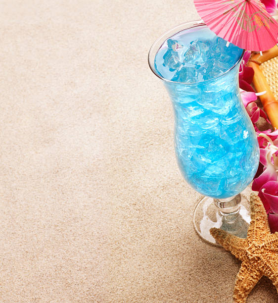 Tropical Drink A Blue Hawaiian tropical drink on the beach. blue hawaiian stock pictures, royalty-free photos & images