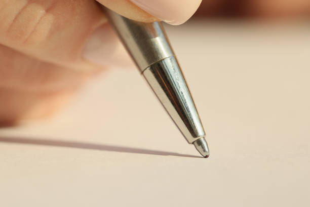 Hand of woman holding iron ball-pen ready to write on blank paper sheet in notepad. Female employee makes notes of project details at work