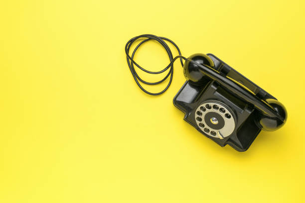 istock A retro black telephone on a yellow background. The old technique. 1827771940