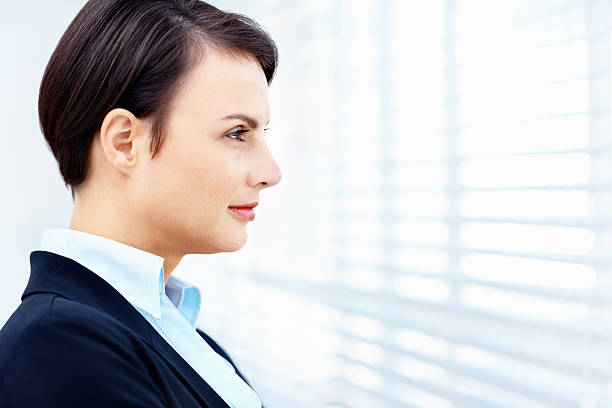 istock Side view of business woman looking through window blinds 182777480