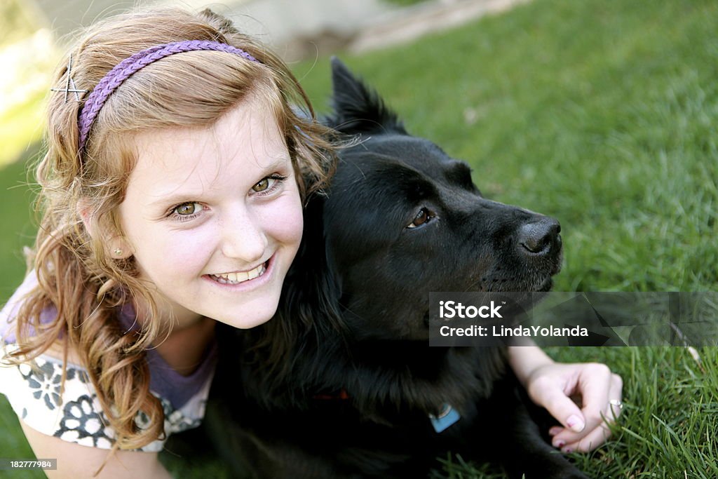 Happy Girl and Dog A beautiful 14 year old girl smiles at the camera as she lays in the grass with her dog. Some copy space. Please view many other images of children and animals in my portfolio. 14-15 Years Stock Photo