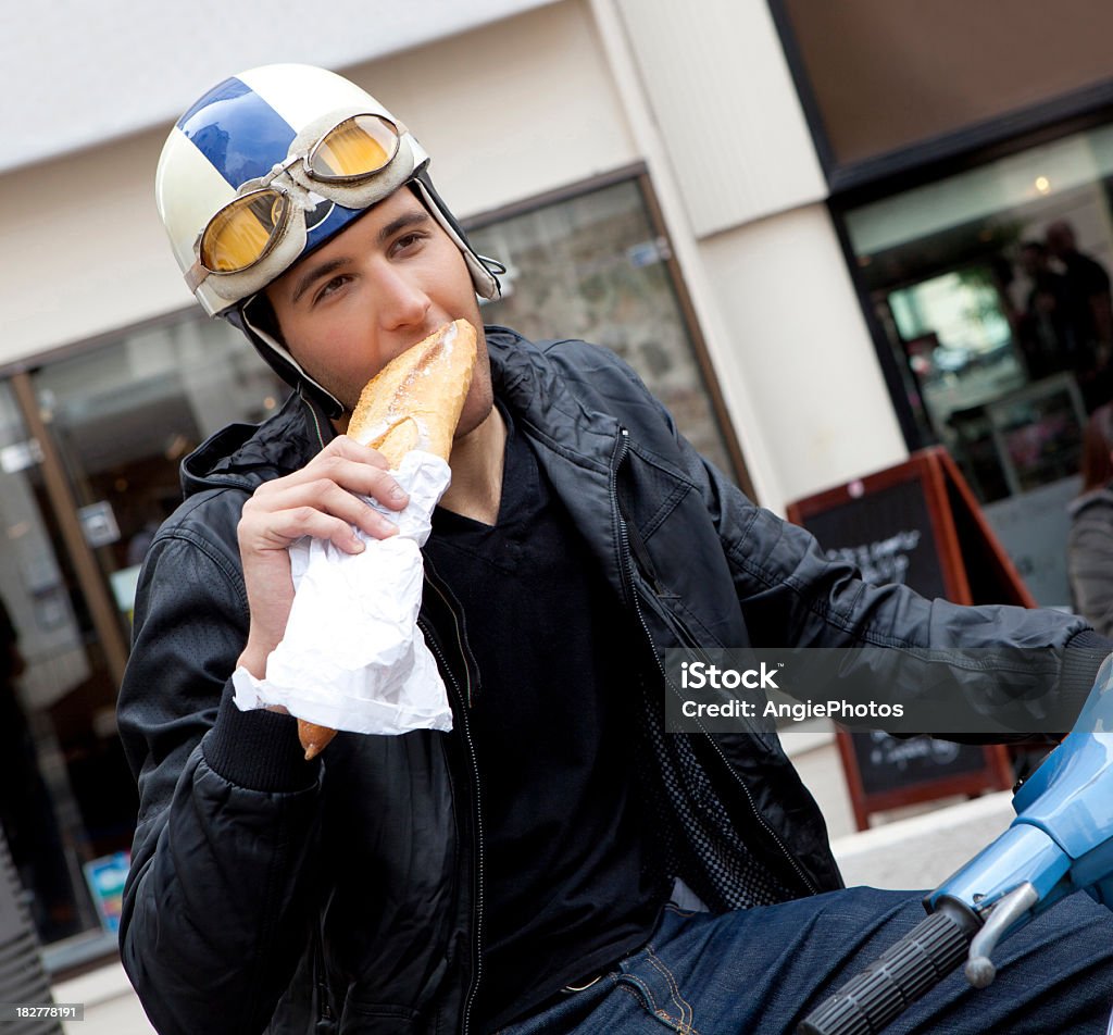 Giovane uomo mangiare baguette su vespa - Foto stock royalty-free di 20-24 anni