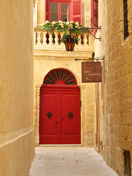 An overhead sign is directing the way to the tea gardens with a red door and balcony in the background. Vertical shot.