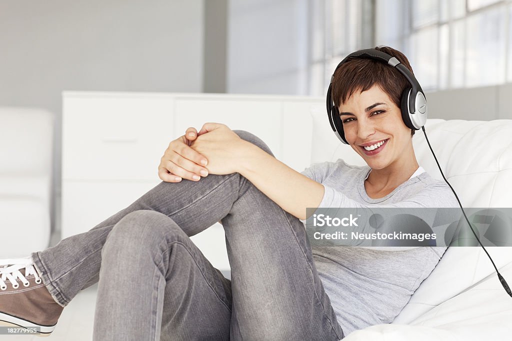 Jeune femme assise sur une chaise avec casque souriant - Photo de Adulte libre de droits